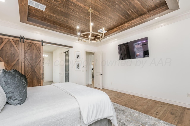 bedroom featuring wooden ceiling, an inviting chandelier, a barn door, a tray ceiling, and hardwood / wood-style flooring