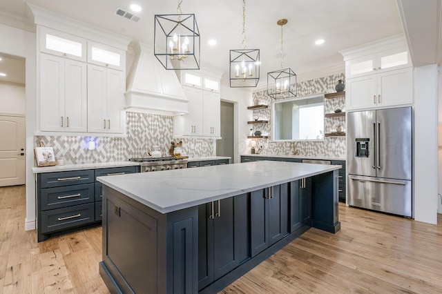 kitchen with crown molding, white cabinetry, stainless steel appliances, and hanging light fixtures