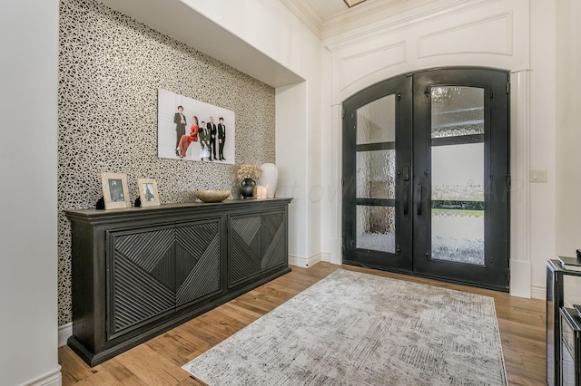 entryway with french doors, ornamental molding, and light wood-type flooring