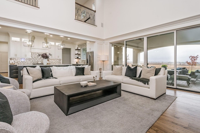 living room with crown molding, a towering ceiling, and light hardwood / wood-style floors