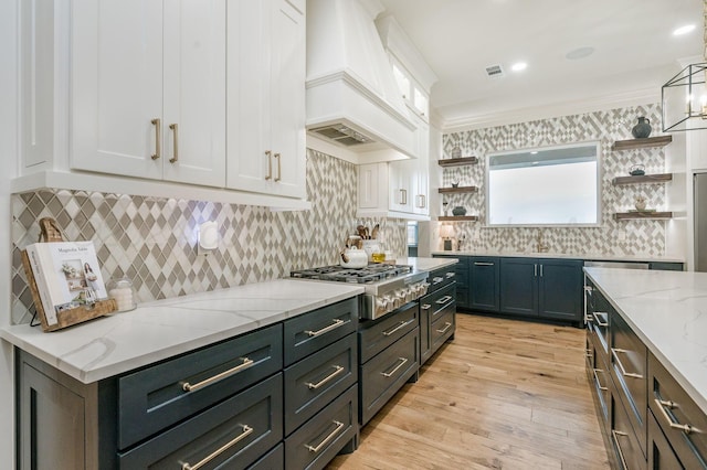 kitchen featuring custom exhaust hood, white cabinets, light hardwood / wood-style floors, light stone counters, and stainless steel gas cooktop