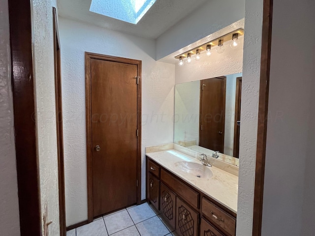 bathroom with vanity, a skylight, and tile patterned floors