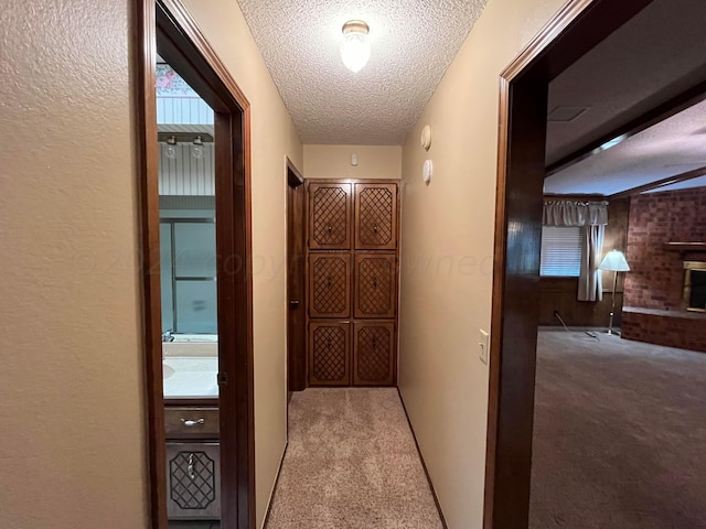 corridor featuring a textured ceiling and light carpet