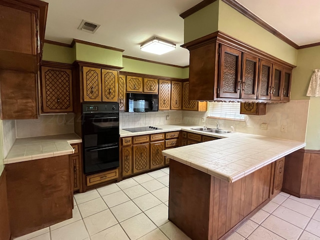 kitchen featuring tile counters, kitchen peninsula, black appliances, and ornamental molding