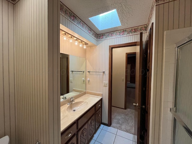 bathroom with tile patterned floors, vanity, a textured ceiling, an enclosed shower, and a skylight