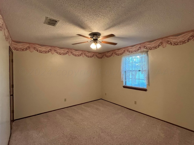 carpeted empty room with ceiling fan and a textured ceiling