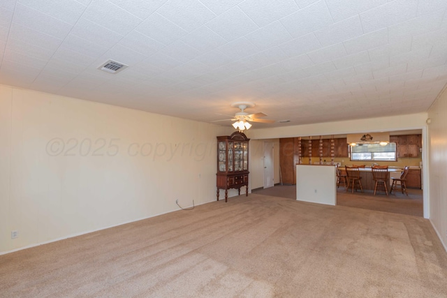 unfurnished living room featuring light carpet and ceiling fan