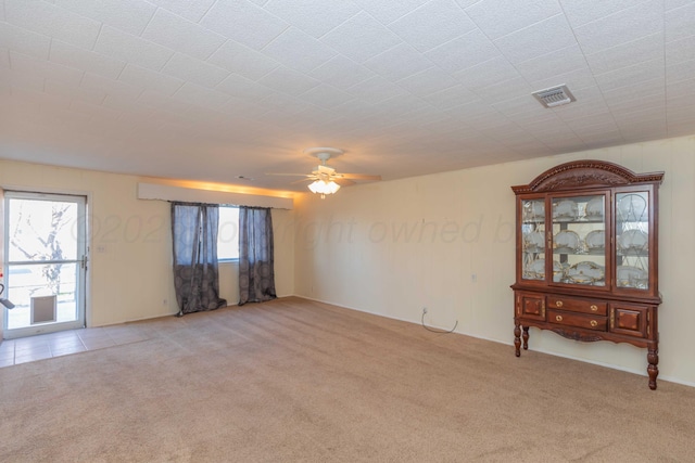 spare room featuring a wealth of natural light, ceiling fan, and light colored carpet