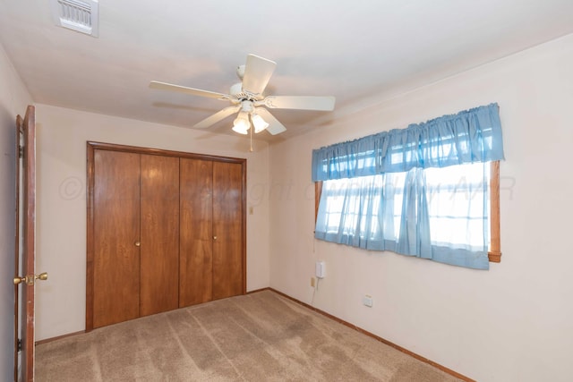 unfurnished bedroom with light carpet, a closet, and ceiling fan