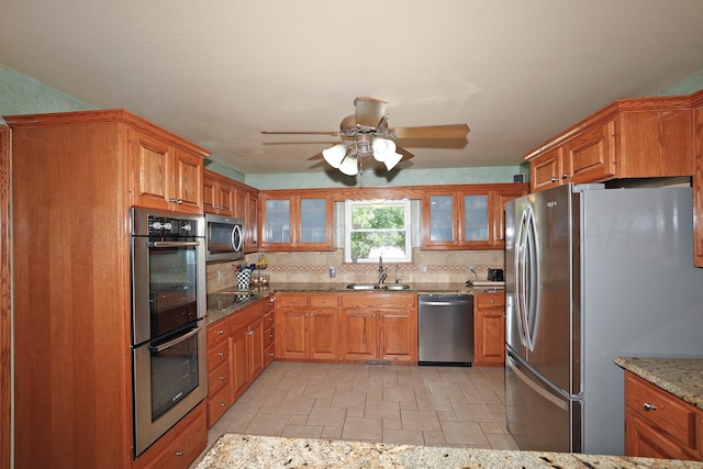 1206 Olive St, Stratford, TX 79084 - kitchen with stainless steel appliances, stone tile flooring, decorative backsplash, and brown cabinets