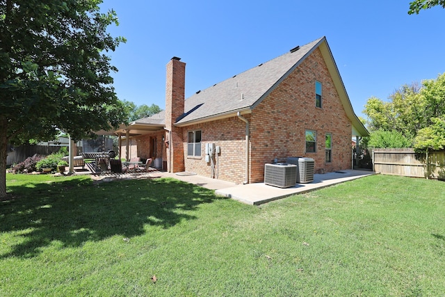 1206 Olive St, Stratford, TX 79084 - back of house with a patio, a chimney, brick siding, and a shingled roof