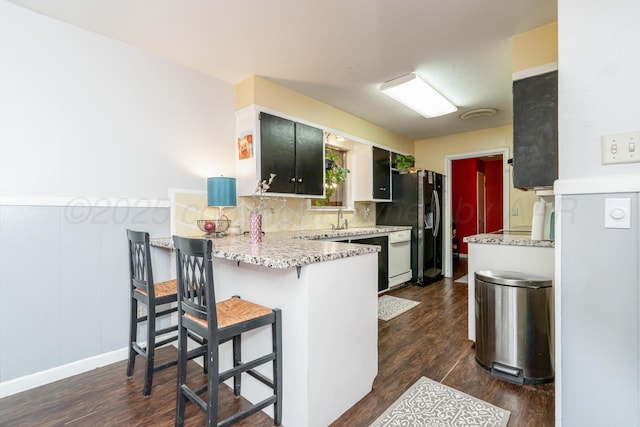 107 Elm St, Hereford, TX 79045 - kitchen featuring a sink, a breakfast bar area, a peninsula, dark wood-style flooring, and stainless steel refrigerator with ice dispenser
