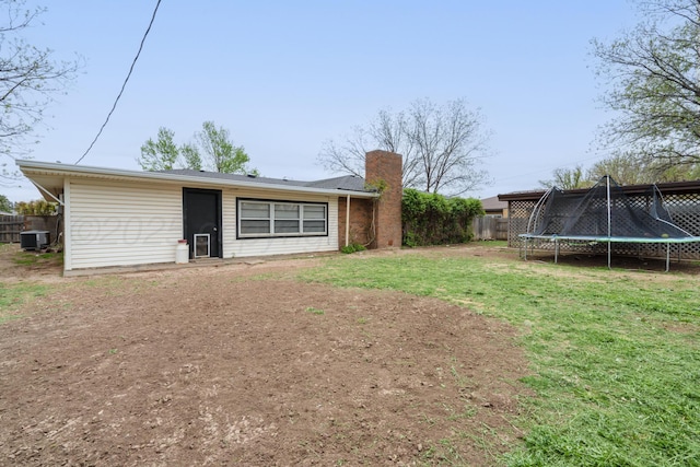 107 Elm St, Hereford, TX 79045 - rear view of house featuring central AC, a chimney, fence, a trampoline, and a yard