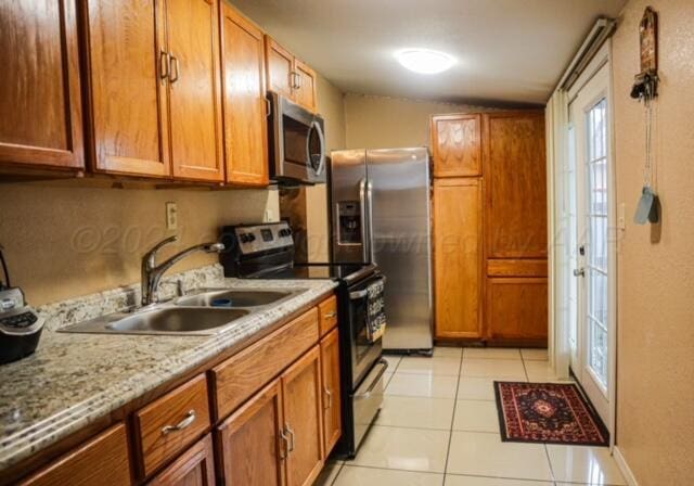 kitchen featuring appliances with stainless steel finishes, light stone counters, light tile patterned flooring, and sink