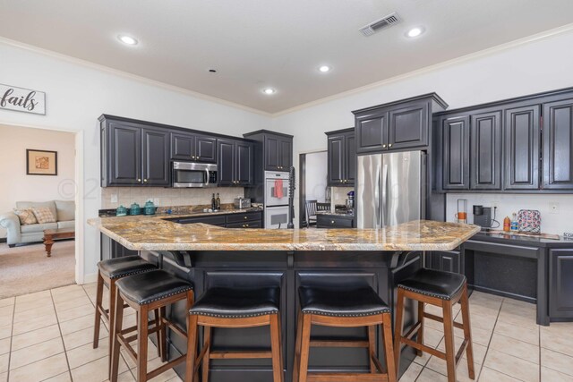 2408 Drake Elm Pl, Amarillo, TX 79124 - kitchen featuring stainless steel appliances, light tile patterned floors, a kitchen breakfast bar, light stone counters, and crown molding