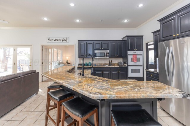 2408 Drake Elm Pl, Amarillo, TX 79124 - kitchen featuring stainless steel appliances, open floor plan, light tile patterned floors, a breakfast bar, and decorative backsplash