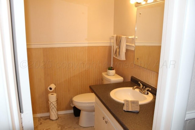 136 NW Dr, Hereford, TX 79045 - half bathroom featuring toilet, vanity, and a wainscoted wall