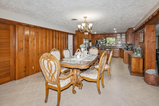 dining area featuring an inviting chandelier, a textured ceiling, and light tile patterned floors