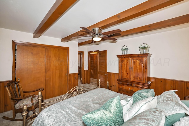 carpeted bedroom with a closet, wainscoting, beam ceiling, and wooden walls