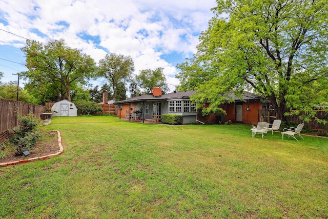 view of yard with a fenced backyard, an outdoor structure, a sunroom, and a shed