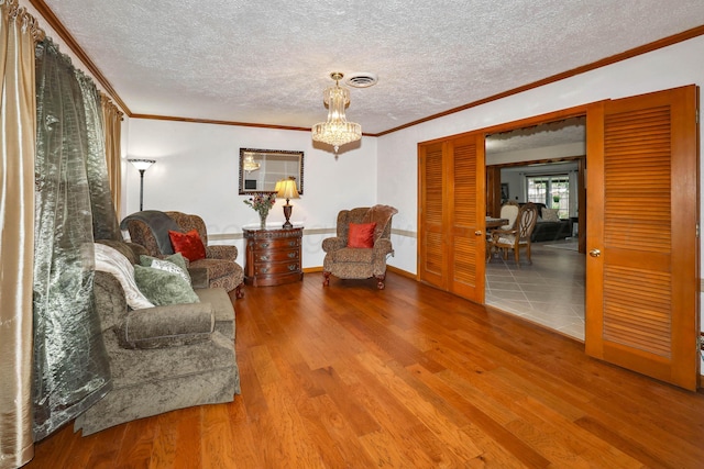 living area with crown molding, wood finished floors, a textured ceiling, and visible vents