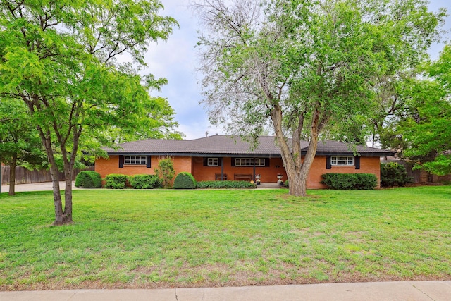 single story home featuring fence, a tile roof, and a front lawn