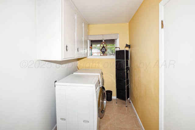 laundry area with light tile patterned floors, baseboards, cabinet space, and washer and clothes dryer