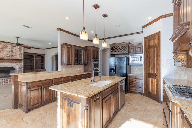 kitchen featuring backsplash, stainless steel appliances, sink, pendant lighting, and a center island with sink