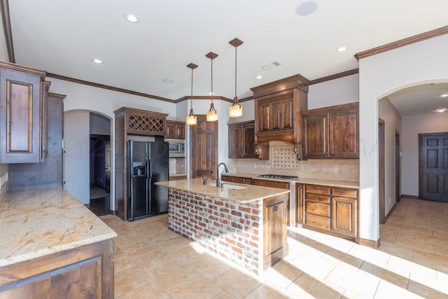 kitchen featuring appliances with stainless steel finishes, tasteful backsplash, sink, pendant lighting, and a center island with sink