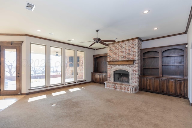 unfurnished living room featuring ceiling fan, light colored carpet, ornamental molding, and a brick fireplace