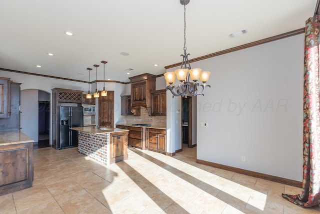 kitchen featuring a kitchen bar, appliances with stainless steel finishes, decorative light fixtures, and a kitchen island with sink