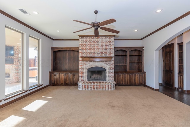 unfurnished living room featuring crown molding, ceiling fan, a fireplace, and dark carpet