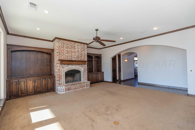 unfurnished living room with carpet flooring, ceiling fan, a fireplace, and ornamental molding