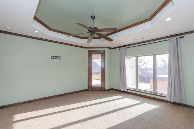 carpeted empty room featuring a raised ceiling, crown molding, and ceiling fan