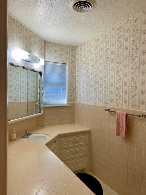 bathroom with vanity, a textured ceiling, and tile walls