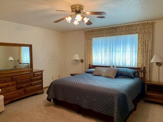 bedroom featuring ceiling fan, a textured ceiling, and light colored carpet