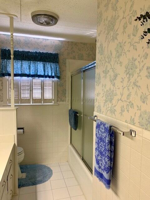 full bathroom with toilet, vanity, tile walls, and a textured ceiling