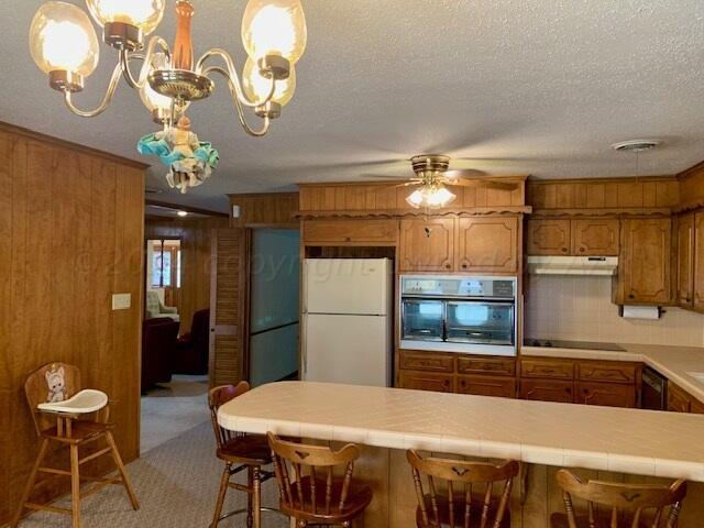 kitchen featuring a kitchen breakfast bar, wooden walls, and black appliances