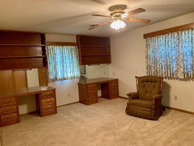 carpeted home office with built in desk, ceiling fan, and a textured ceiling