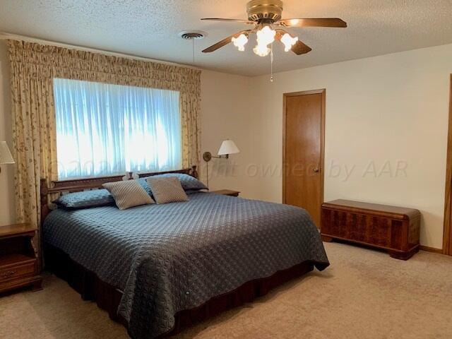 carpeted bedroom featuring ceiling fan and a textured ceiling