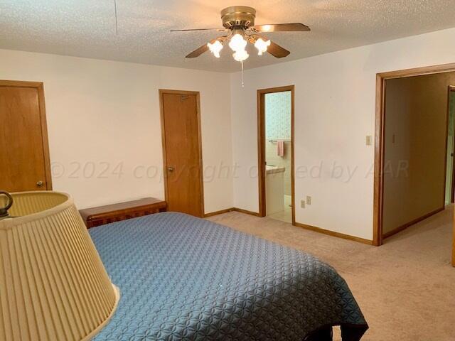 bedroom featuring ceiling fan, a textured ceiling, light carpet, and connected bathroom