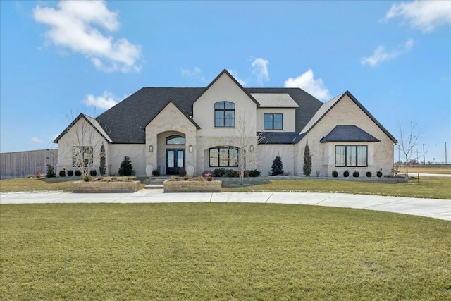 french country style house featuring fence, a front lawn, and french doors