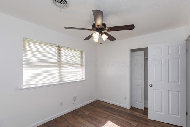unfurnished bedroom featuring dark wood finished floors, baseboards, a ceiling fan, and a closet