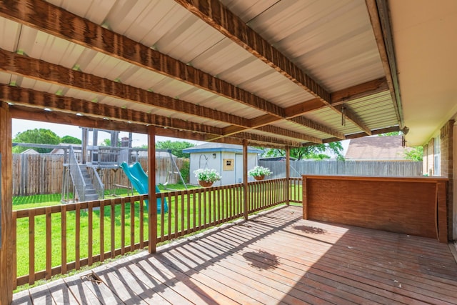 wooden terrace with a playground, a storage shed, and an outbuilding