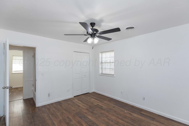 unfurnished bedroom with dark wood-style flooring, baseboards, a closet, and a ceiling fan