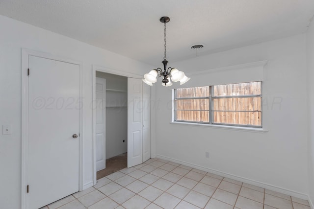 unfurnished dining area featuring a chandelier and baseboards