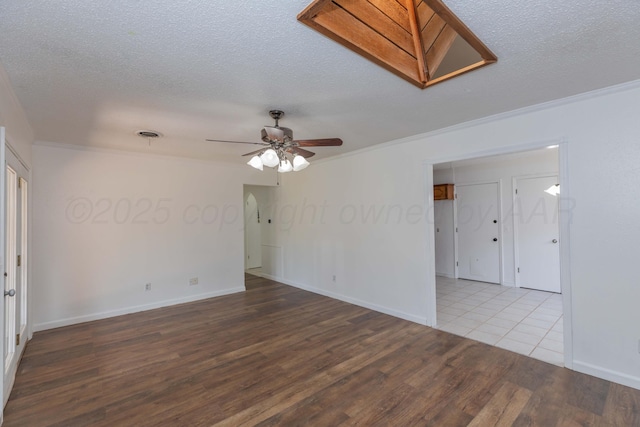 empty room featuring wood finished floors, ceiling fan, crown molding, a textured ceiling, and baseboards