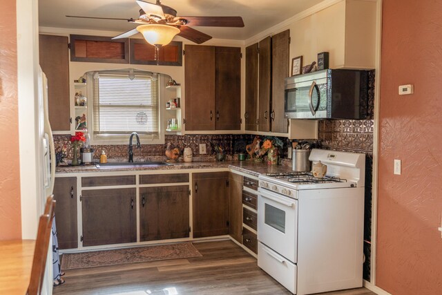 1002 S Main St, Wheeler, TX 79096 - kitchen with white gas range, stainless steel microwave, a ceiling fan, backsplash, and wood finished floors