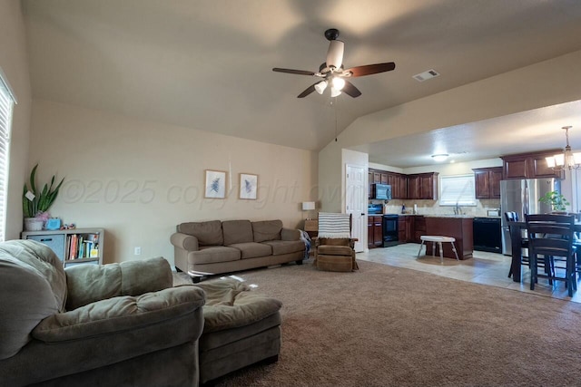 living room with light carpet, visible vents, ceiling fan with notable chandelier, and vaulted ceiling