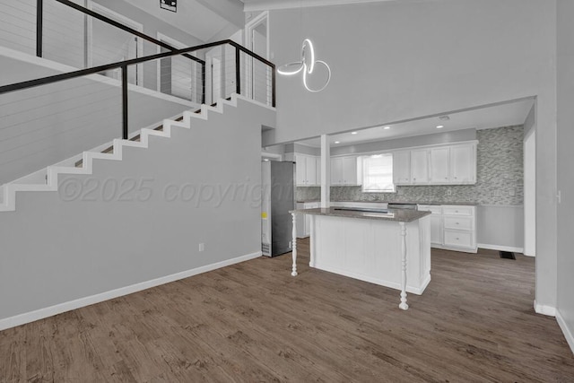 3700 Paramount Blvd, Amarillo, TX 79109 - kitchen featuring refrigerator, white cabinets, dark wood-style flooring, a towering ceiling, and a center island